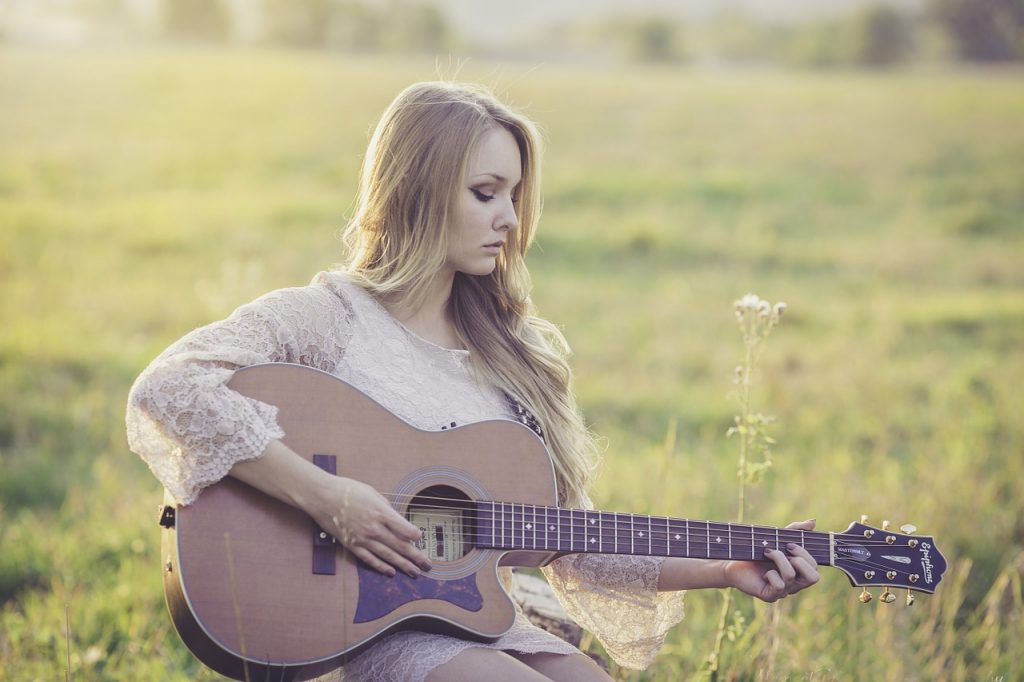 Frau spielt Gitarre in der Natur.